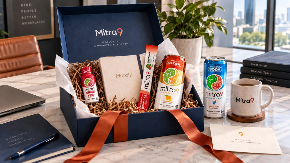 Mitra9 corporate gift box featuring functional drinks, a Mitragynine shot, drink mix, branded notebook, and office gift items arranged in a professional workspace.