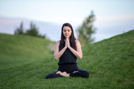 A person meditates outdoors after drinking kava tea