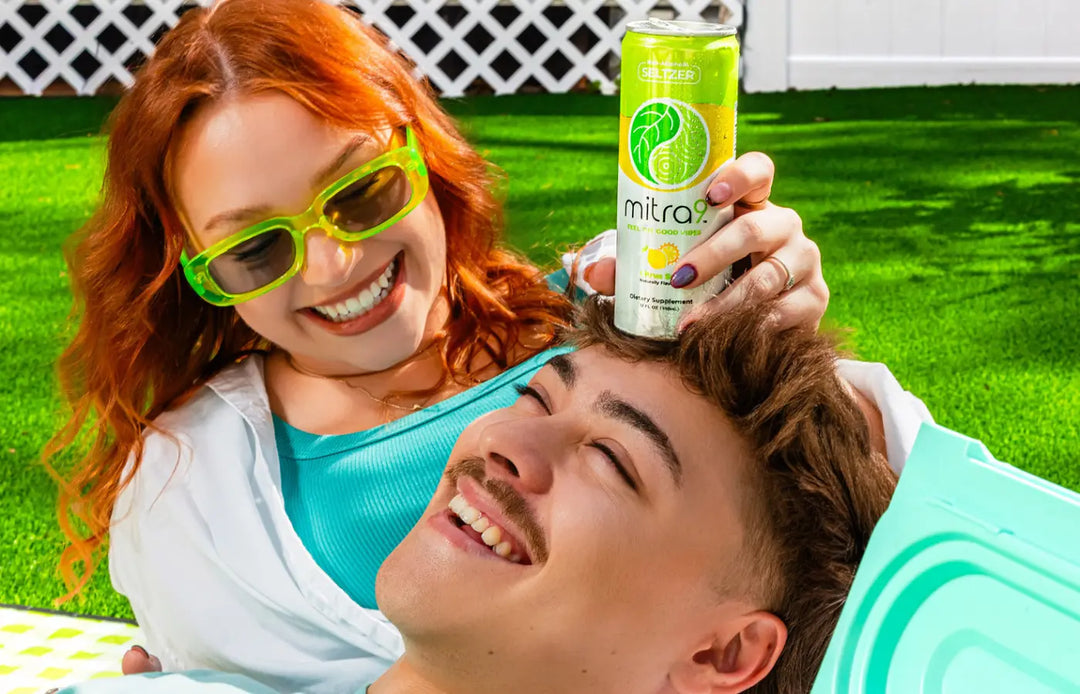 Couple relaxing outdoors on a sunny day with Mitra9 functional drink kava soda can, lifestyle scene featuring refreshing non-alcoholic seltzer for calm, social vibes and relaxation