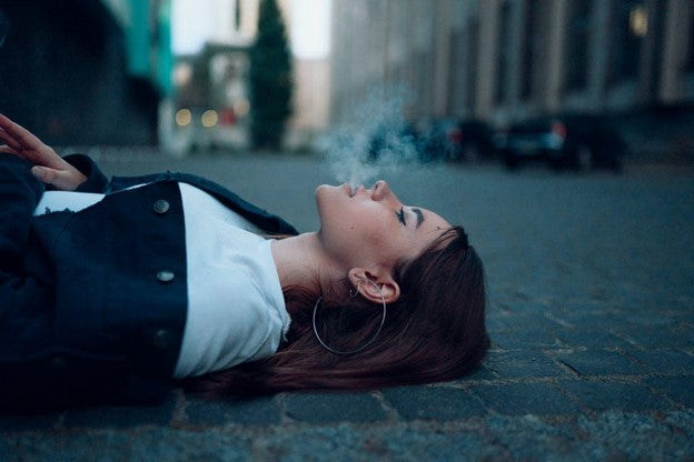 Girl Smoking kratom laying on the road