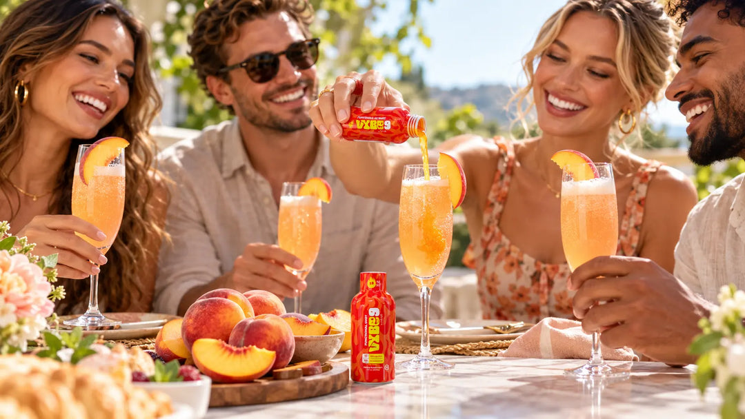 Friends enjoying sparkling peach bellini mocktails at an outdoor brunch, featuring fresh peach garnishes and a Vybe9 Fire Shot being poured into a glass.