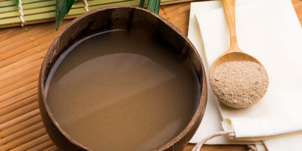 Coconut bowl filled with traditional Kava and a spoonful of Kava root powder, representing how Kava is prepared